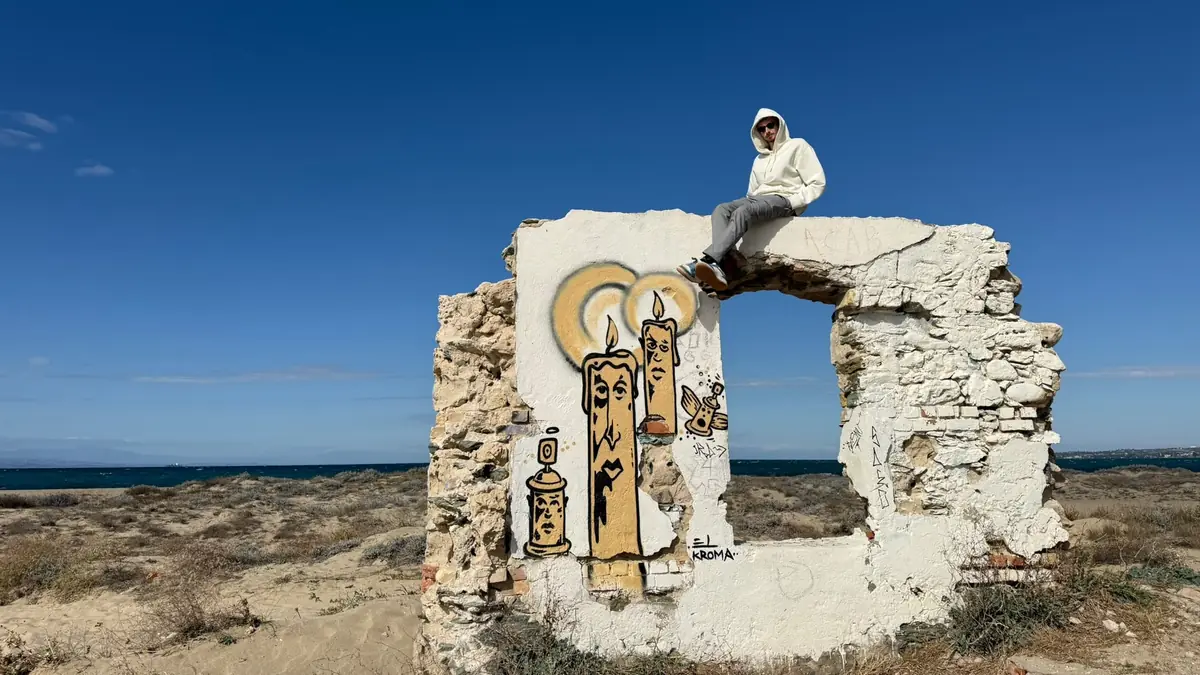 Sitting on a ruined wall with graffiti candles by the sea