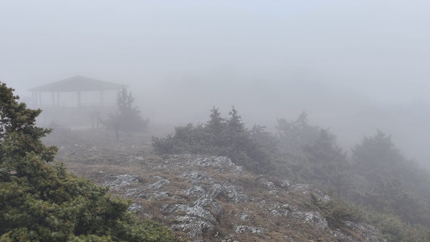 A gazebo in thick fog on a rocky summit