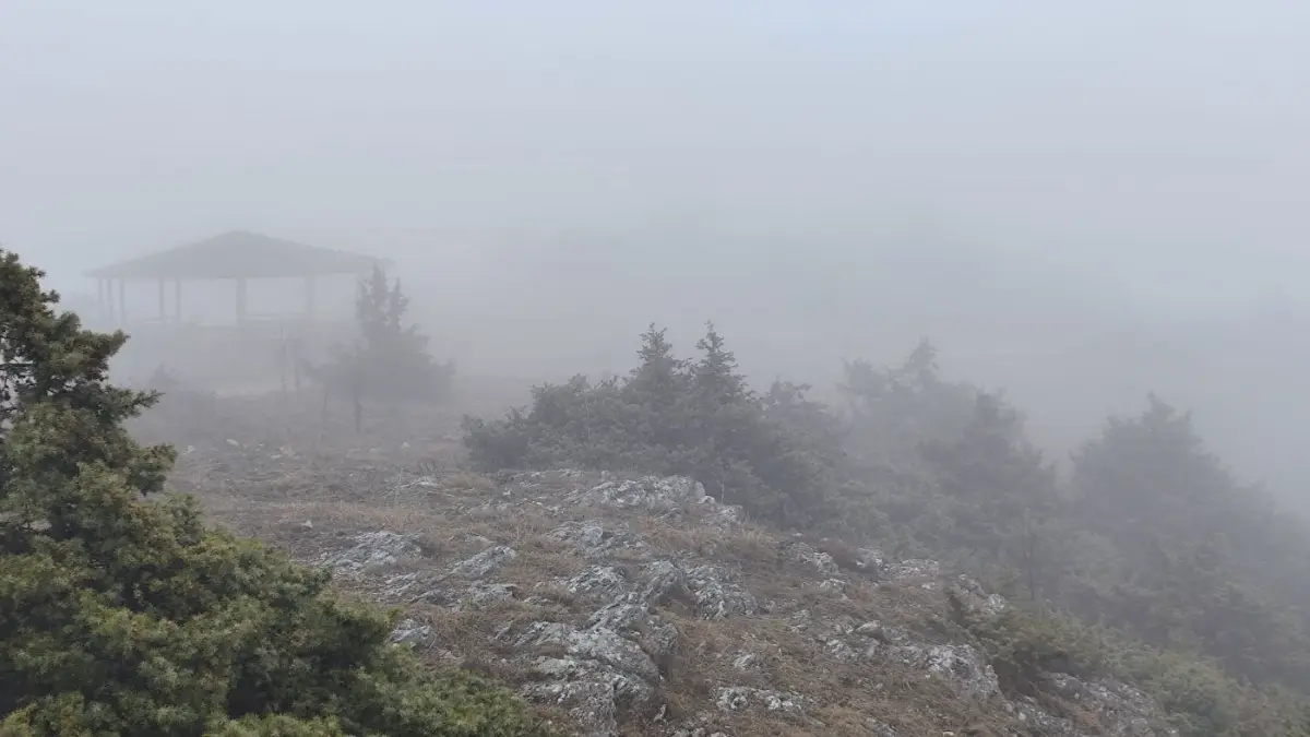 A gazebo in thick fog on a rocky summit
