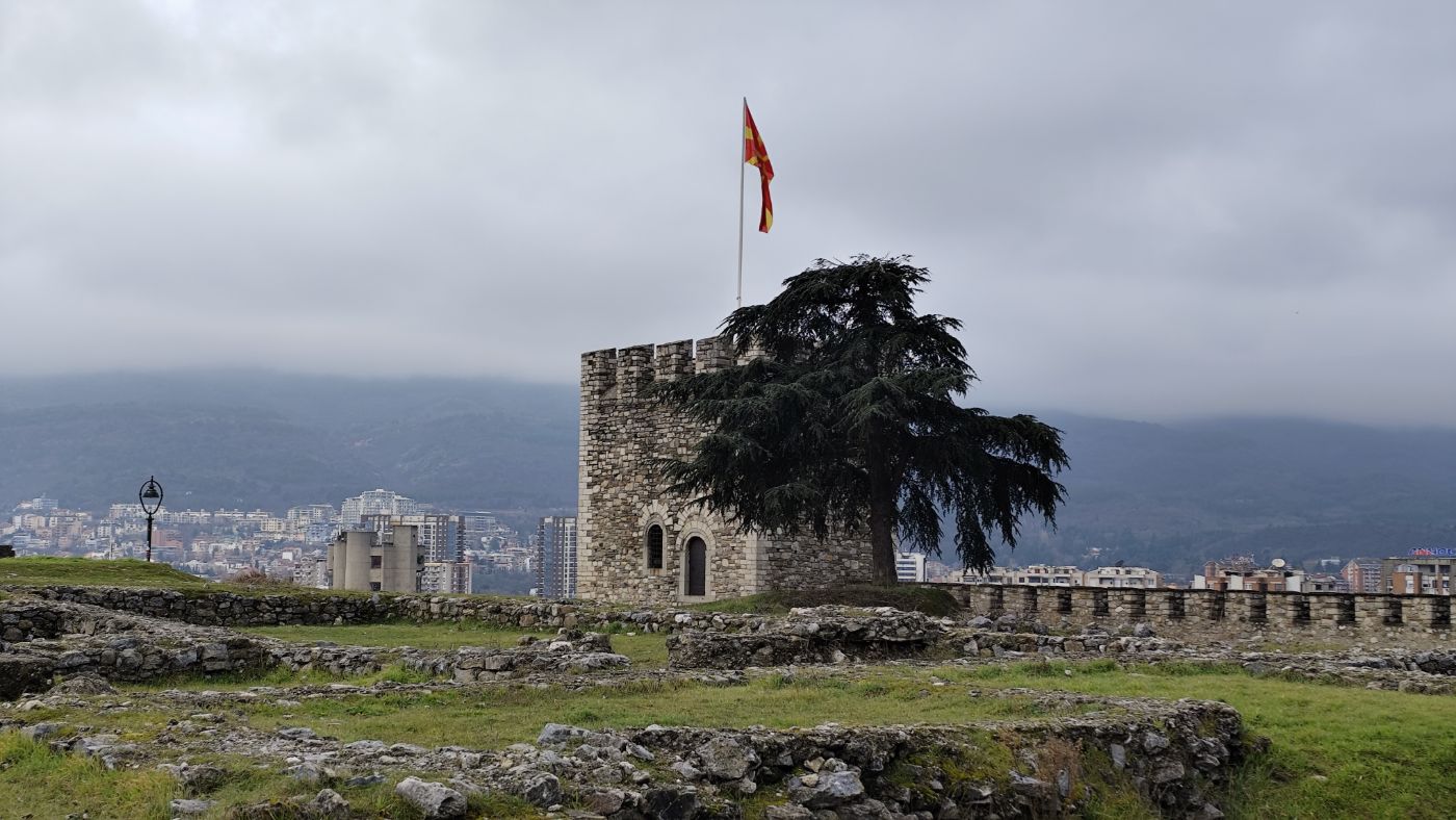 A fortress tower with a flag under grey clouds