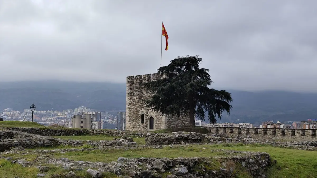 A fortress tower with a flag under grey clouds