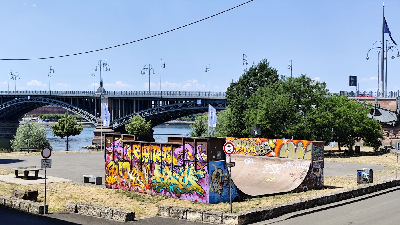 A graffiti skate ramp by a river bridge